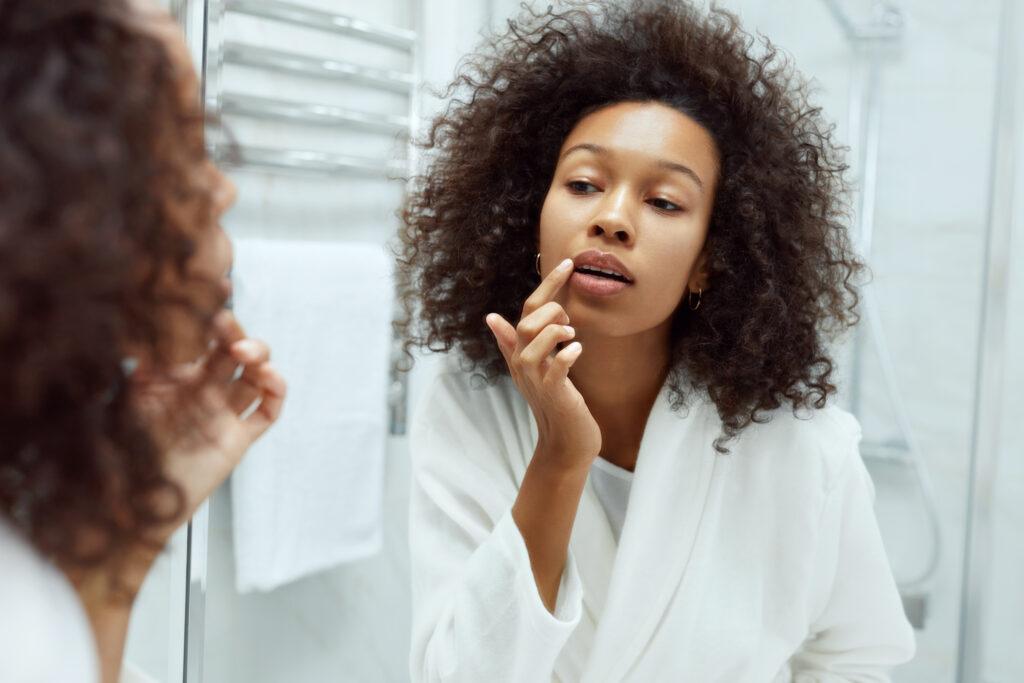 Lips skin care. Woman applying lip balm in bathroom portrait