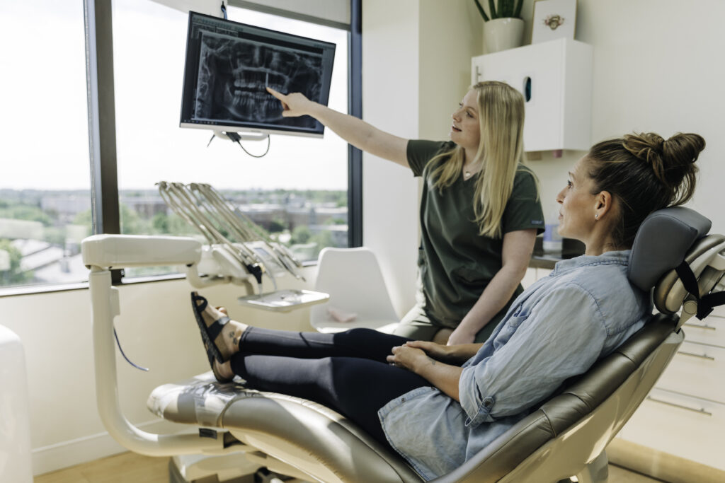 Denver dental team member reviewing a panoramic dental X-ray with a patient before zirconia dental implant treatment