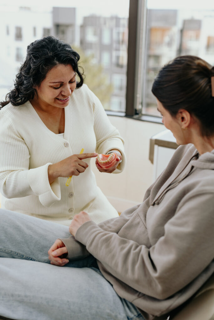 Dental professional showing a patient how to care for teeth and gums to improve poor dental hygiene